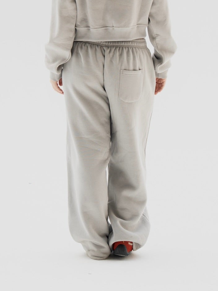 Person wearing a light gray tracksuit on a white background